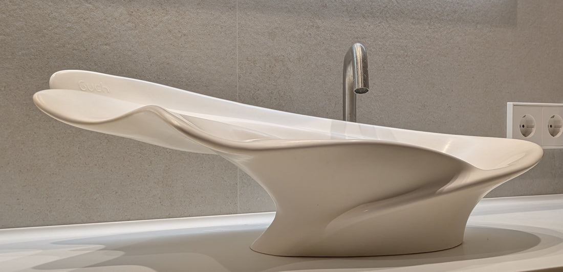 Lavabo Deneb blanco de Solid Surface sobre encimera, con bordes orgánicos ondulados.